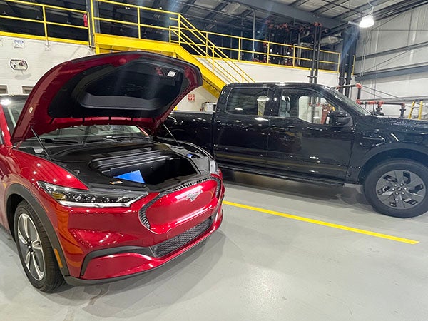 Two electric vehicles. A red Model Y LR AWD and a black  F-150 Lightning ER.